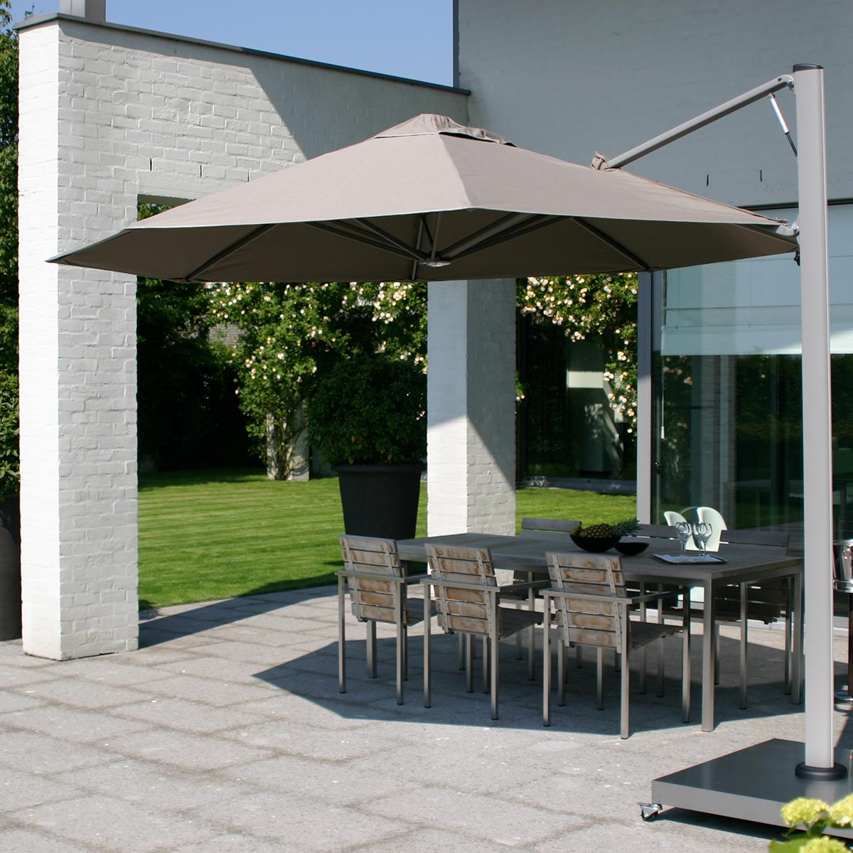 Stor parasol der skaber skygge over havemøbler, der står ved et hvidt hus.
