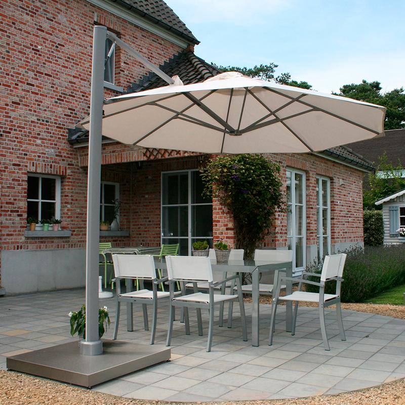 Parasol ved et rødt murstenshus som danner skygger over nogle havemøbler, der står på en rund terrasse.