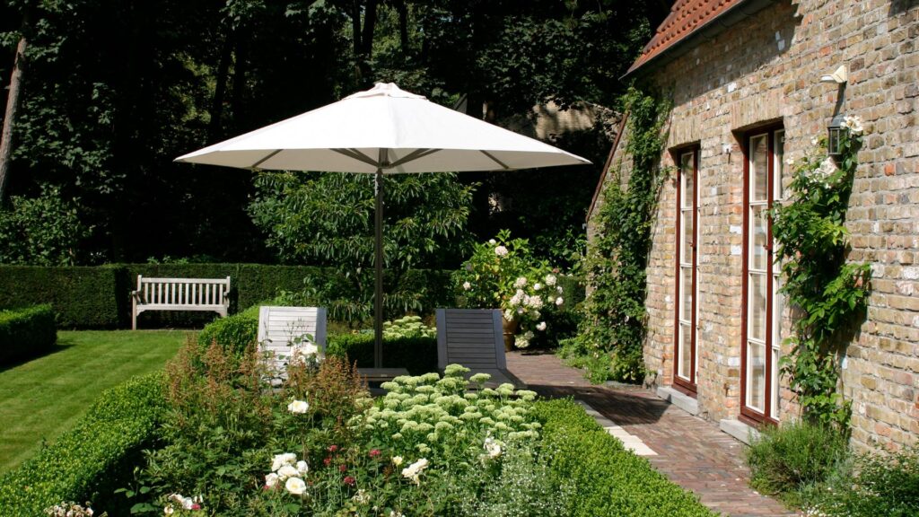 En hvid parasol i en grøn have en sommerdag.