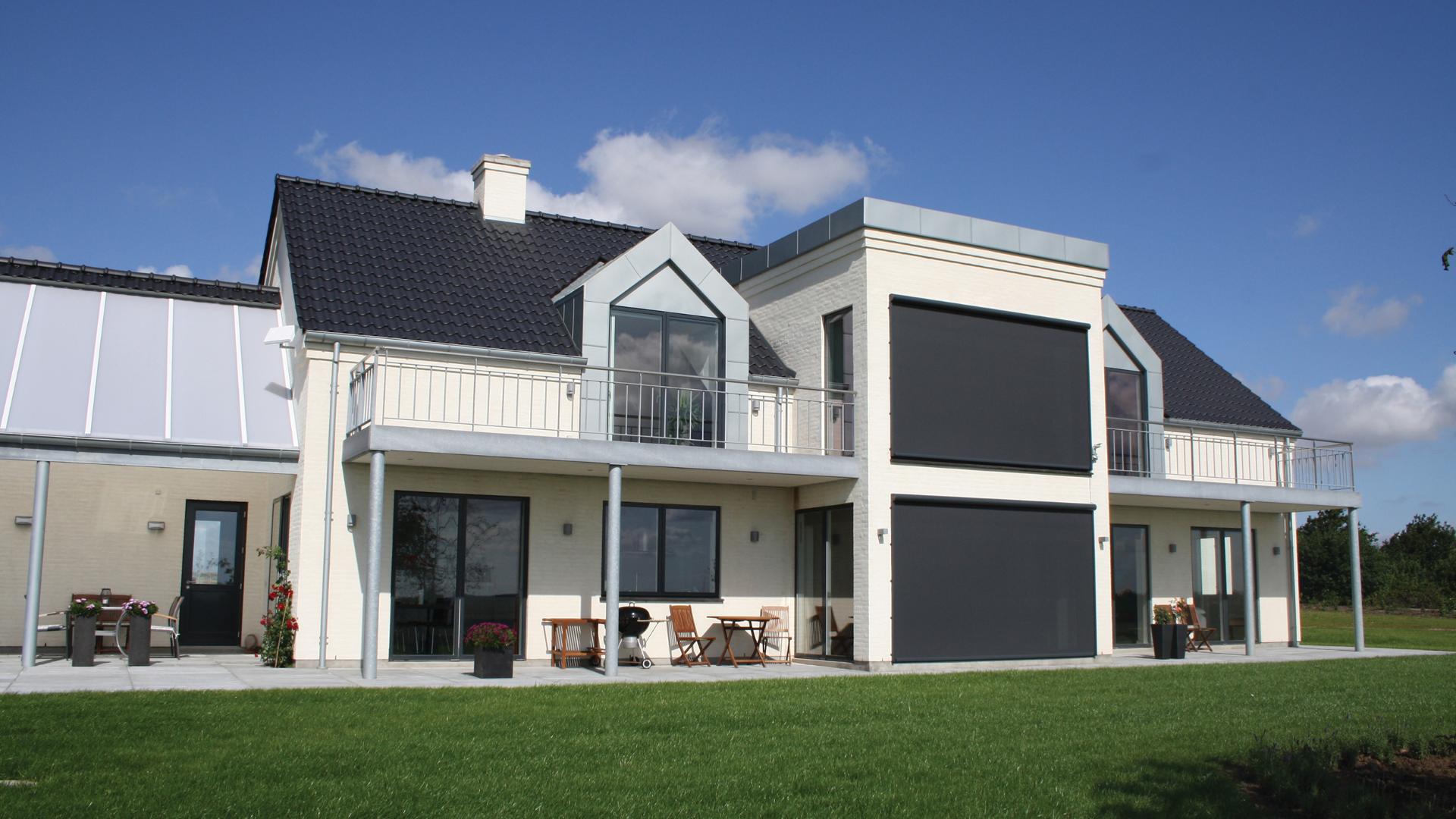 Et stort hvidt hus med store vinduespartier, der er lukket for af screens.