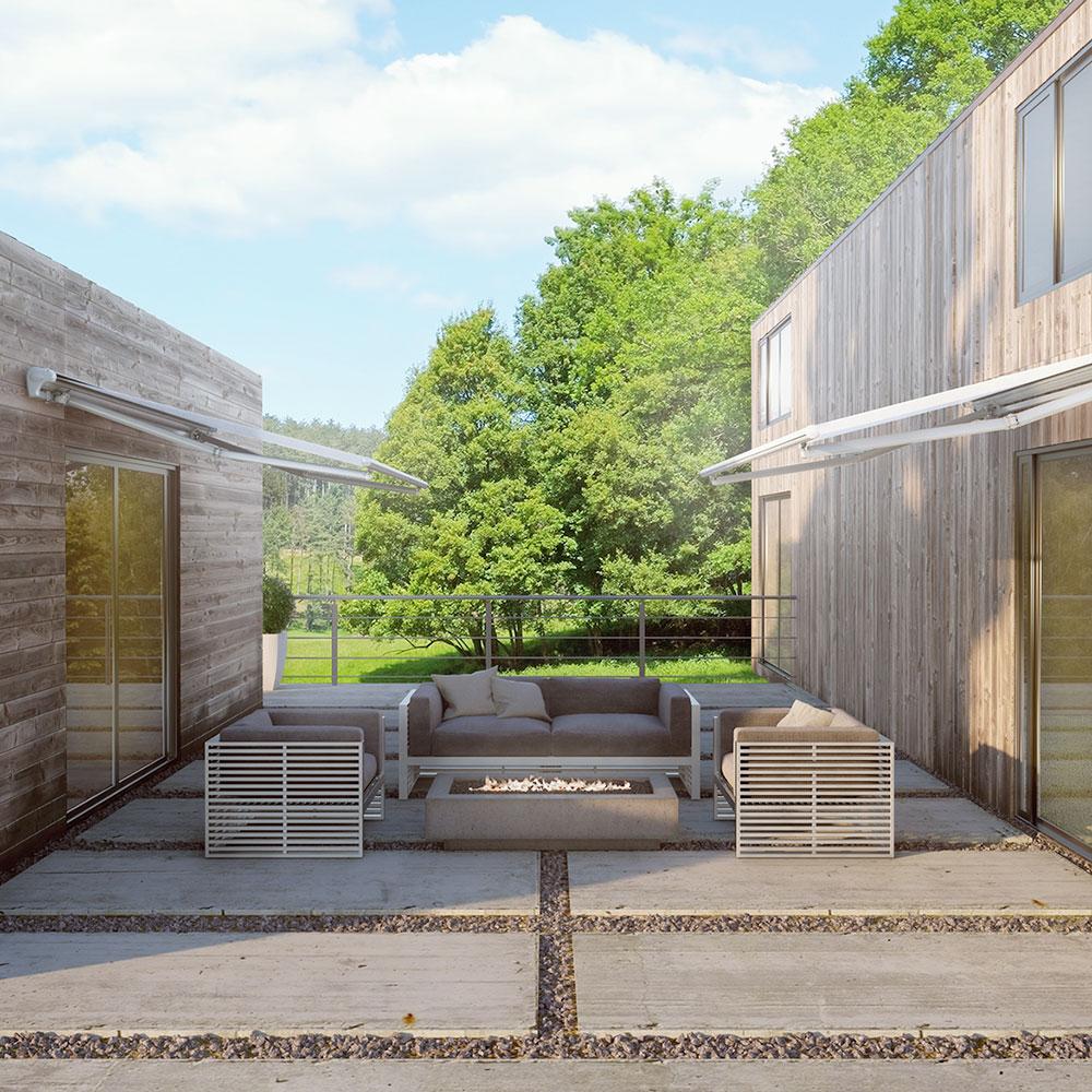 Markiser på to træbeklædte huse, der vender ind mod hinanden og har en fælles terrasse mellem dem.
