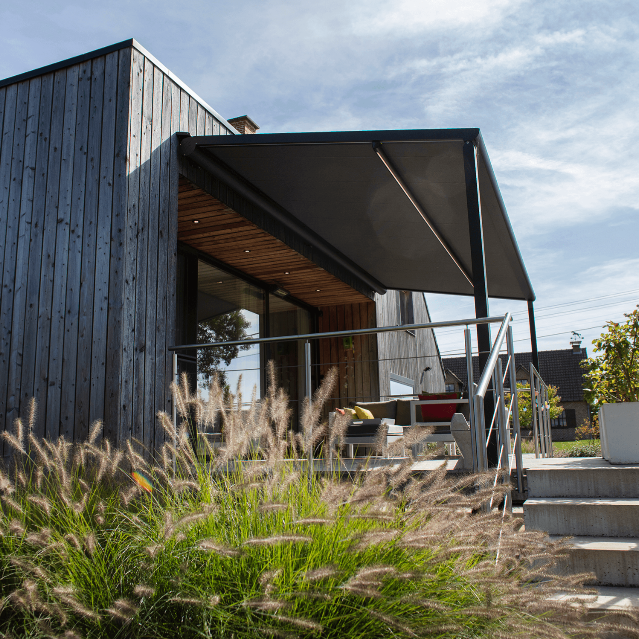 Pergola med motor der står ud fra huset og overdækker terrassen.
