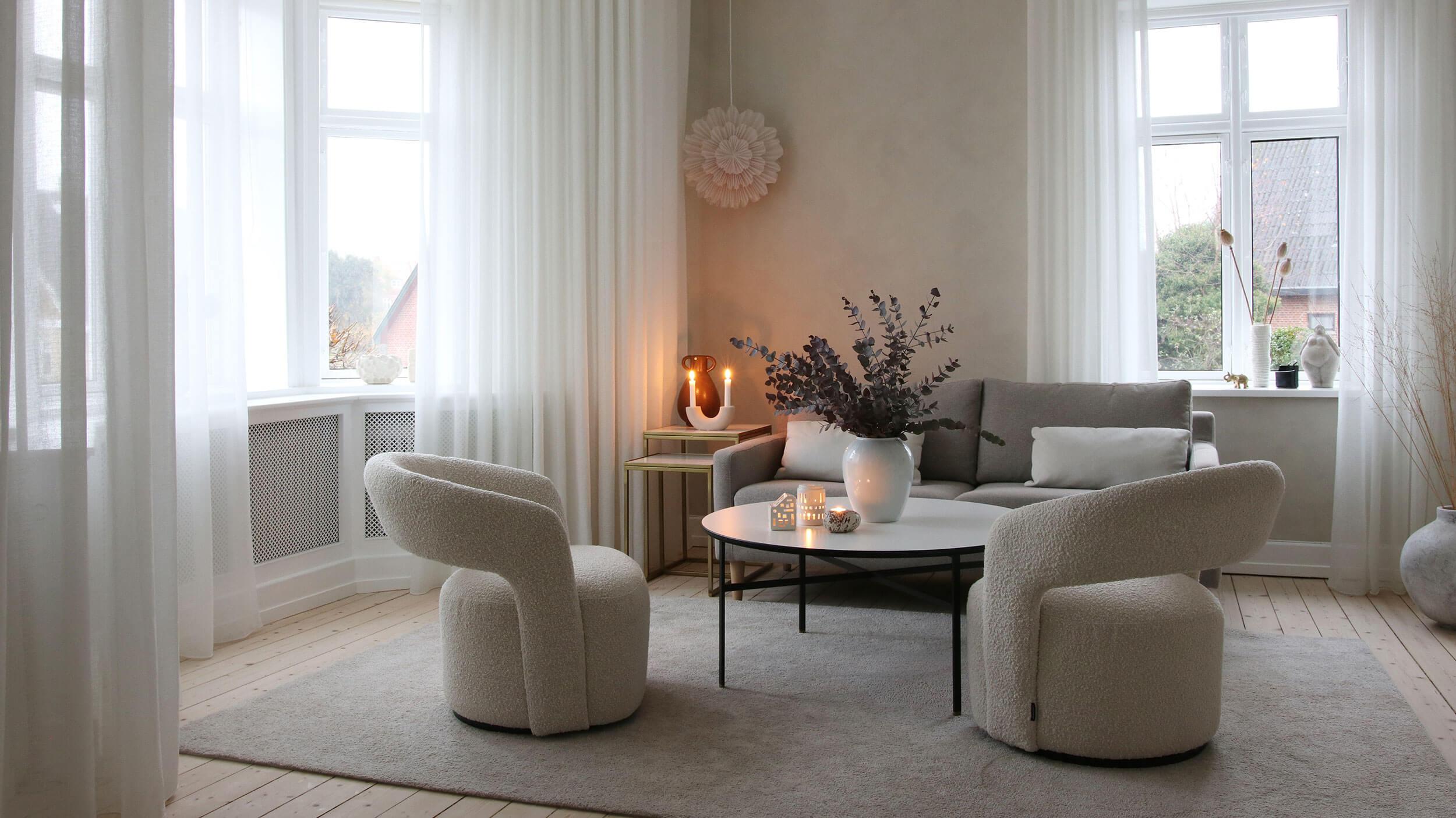 Lyse lette stofgardiner i en stue med stole og tæppe i beige.